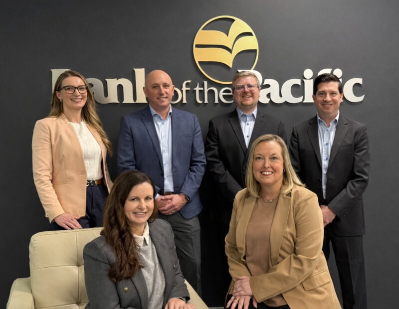 Bank of the Pacific's Commercial Real Estate team pose in front of a wall with the Bank of the Pacific logo.
